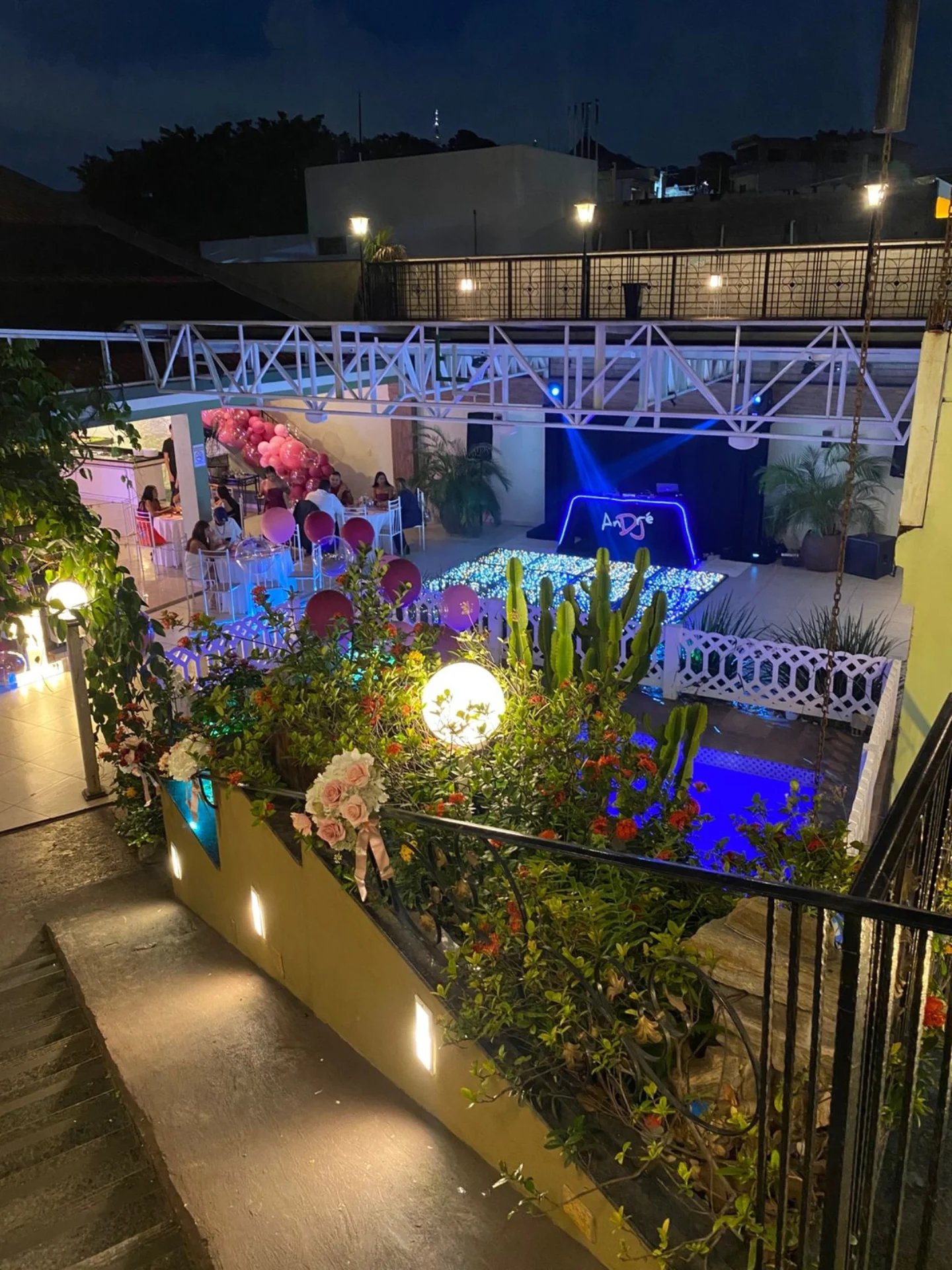 Vista panorâmica noturna do espaço com pista de dança iluminada e jardim